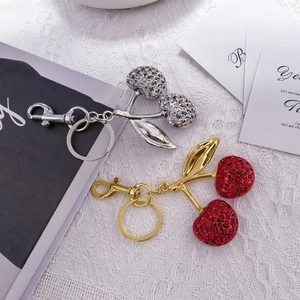 Detail of red and white crystal cherry keychains with gold and silver metal finishes