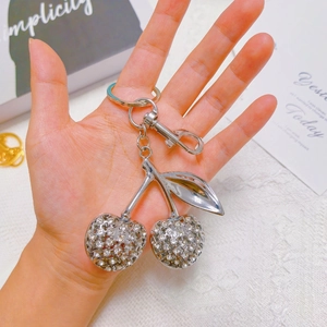 Close-up of a sparkling crystal cherry keychain featuring silver hardware in a lifestyle setting