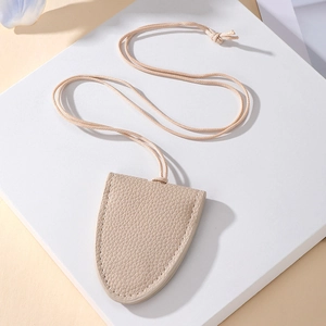Detailed view of beige lychee grain leather clochette necklace with fine stitching and cord
