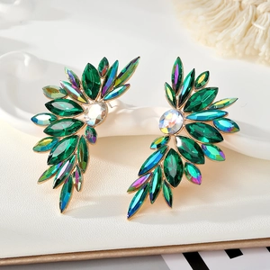 Detail of gold-tone wing earrings with marquise-cut green crystals and sparkling gems
