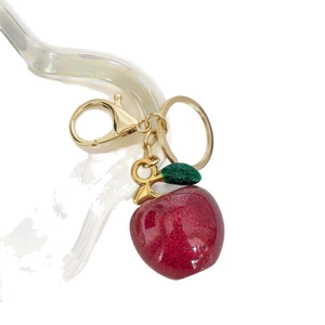 Exquisite apple keychain with red glitter fill and gold leaf on a sleek white backdrop