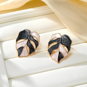 Detail view of monstera leaf earrings with pink and black enamel on gold plating