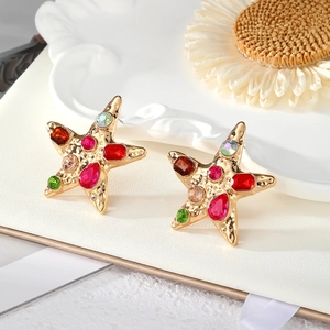 Macro view of gold starfish earrings featuring colorful rhinestones and vintage texture