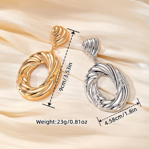 Minimalist large twisted oval hoop earrings in polished gold and silver metal finishes