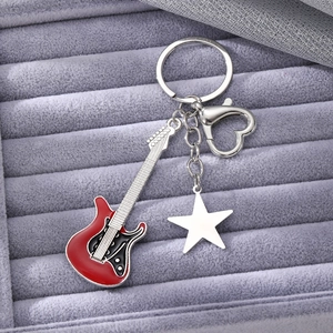 Detail of red electric guitar and silver star charms with a heart-shaped keychain hook