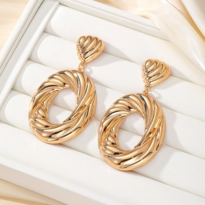 Close-up of golden oversized oval hoop earrings with twisted texture in a white jewelry box
