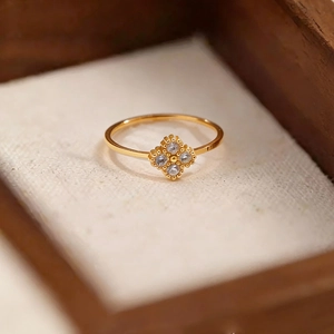 Bague trèfle minimaliste en or avec diamants sur un fond de boîte à bijoux chaleureux