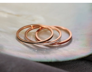 Macro shot of rose gold rings with black, white, and red enamel inlays on a shell