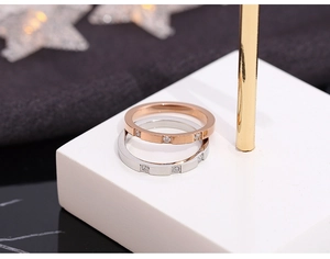 Close-up of rose gold and silver titanium rings with three inset square crystals on a stand