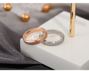 Detail of rose gold and silver rings with frosted texture and polished edges on stand