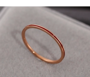 Close-up of a minimalist rose gold stainless steel ring with red enamel inlay on velvet