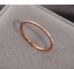 Detail shot of rose gold thin ring with white enamel inlay on a grey velvet box