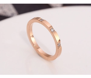 Macro detail of rose gold ring with three inset diamonds and polished finish