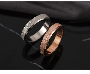 Detail of rose gold and silver rings with matte sandblast finish on black marble surface