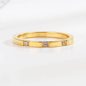Macro shot of gold stainless steel ring featuring three inset diamonds on a smooth band