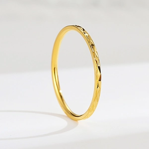 Macro de un anillo minimalista de acero inoxidable dorado con superficies de corte geométrico