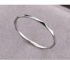 Macro shot of silver geometric faceted titanium steel ring with thin band and polished edges