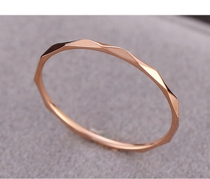 Macro shot of rose gold V-shaped thin geometric ring with faceted surface textures