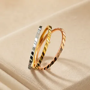 Dettaglio macro di tre anelli minimalisti in acciaio testurizzato oro e argento