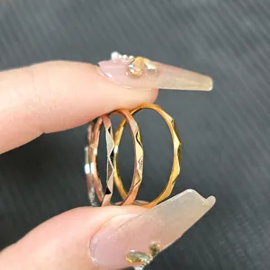Close-up of three minimalist faceted V-shape rings in silver, gold, and rose gold finish