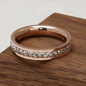 Detail of rose gold eternity band with channel-set square cut crystals on wood base