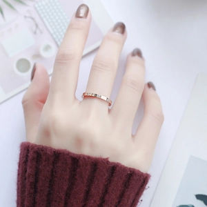 Nahaufnahme eines roségoldenen Titanrings mit drei Diamanten am Finger eines Models