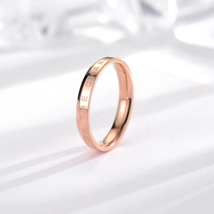 Minimalist rose gold titanium ring with BE THE CHANGE engraving on white background