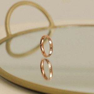Close-up of rose gold minimalist ring with BE THE CHANGE engraving on polished surface