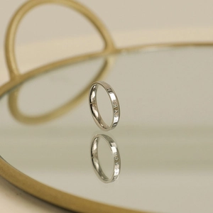 Polished stainless steel ring with 'BE THE CHANGE' engraving on a mirror tray