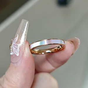 Detailopname van roségouden titanium ring met witte schelp inleg in de hand