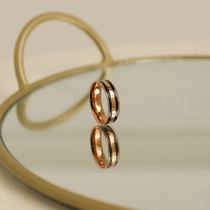 Macro shot of rose gold ring with black inlay and THE CHANGE engraving on mirror surface
