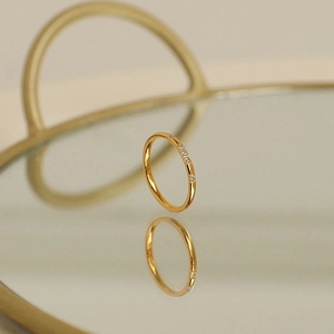 Macro de un anillo fino minimalista bañado en oro de 18k con pequeñas piedras de circonita