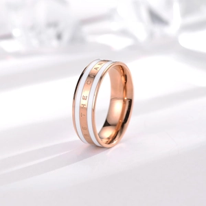 Detail of rose gold ring with white inlay and 'BE THE CHANGE' engraved text