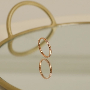 Elegante anillo de titanio chapado en oro rosa de 18k con circonitas y reflejo en el espejo