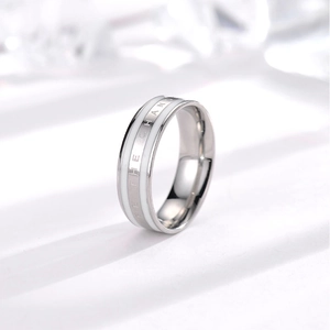Macro detail of stainless steel ring featuring white enamel inlay and Be The Change engraving