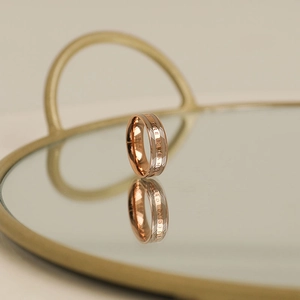 Detailed shot of rose gold stainless steel ring with The Change engraving on mirror tray