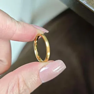 Nahaufnahme eines schmalen, 18 Karat vergoldeten Edelstahlrings zwischen Fingern