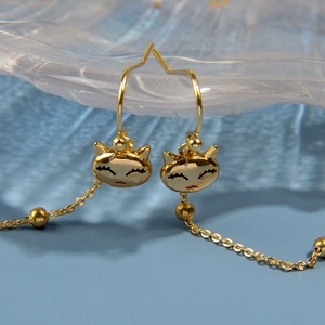 Vue macro du pendentif tête de chat dorée avec longue chaîne sur fond bleu mat