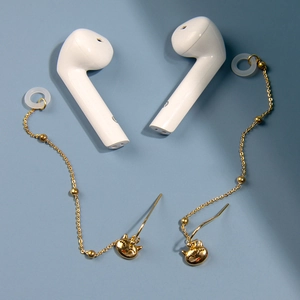 Détail de boucles d'oreilles dorées chat de la chance avec boucles en silicone pour écouteurs