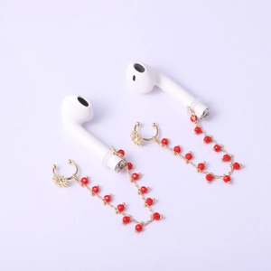 Détail de clips d'oreilles marguerites dorées avec perles rouges pour écouteurs sans fil