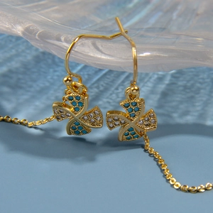 Détail de boucles d'oreilles moulin à vent dorées avec zircons bleus et longues chaînes