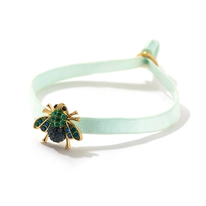 Detaillierte Makroansicht des Bienenanhängers mit grünen und blauen Kristallen am Gummiband