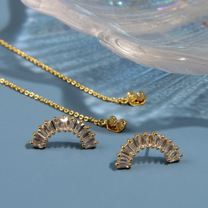 Vue macro de boucles d'oreilles arc-en-ciel dorées avec zircons et chaînes fines reliées