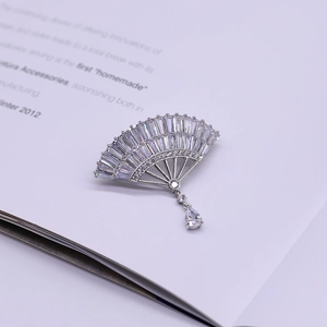 Elegant silver fan brooch with pavé zircon stones and teardrop pendant on magazine