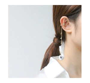 Détail du bijou d'oreille étoile dorée avec chaîne anti-perte et pendentif casque