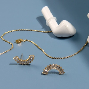 Détail d'une chaîne anti-perte dorée avec zircons carrés pour écouteurs sans fil