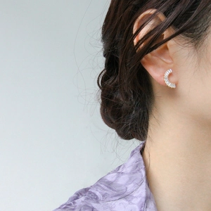 Gros plan de boucles d'oreilles C dorées avec cristaux baguette portées par un mannequin