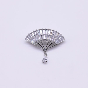Macro detail of a fan-shaped silver brooch with zircon stones and a teardrop pendant