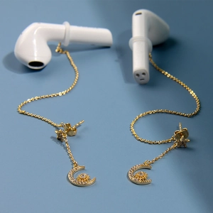 Détail de boucles d'oreilles anti-perte dorées avec lune, étoiles et zircons pour écouteurs