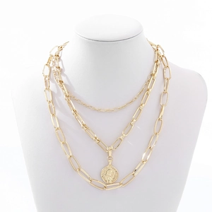 Close-up of layered gold coin necklace with chunky curb chains and vintage portrait pendant